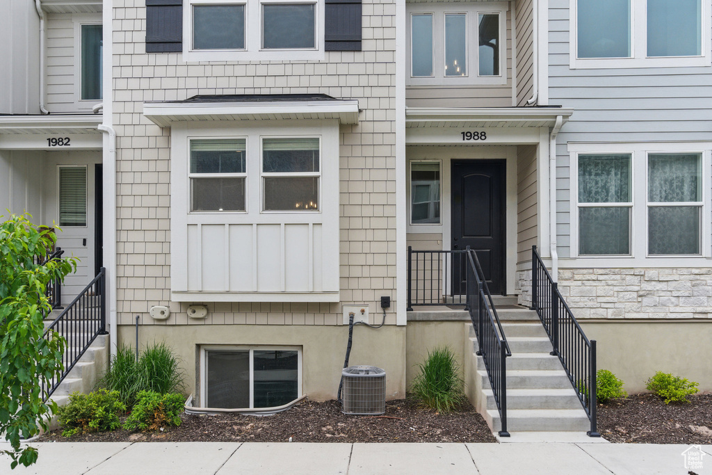View of exterior entry featuring cooling unit and stone siding