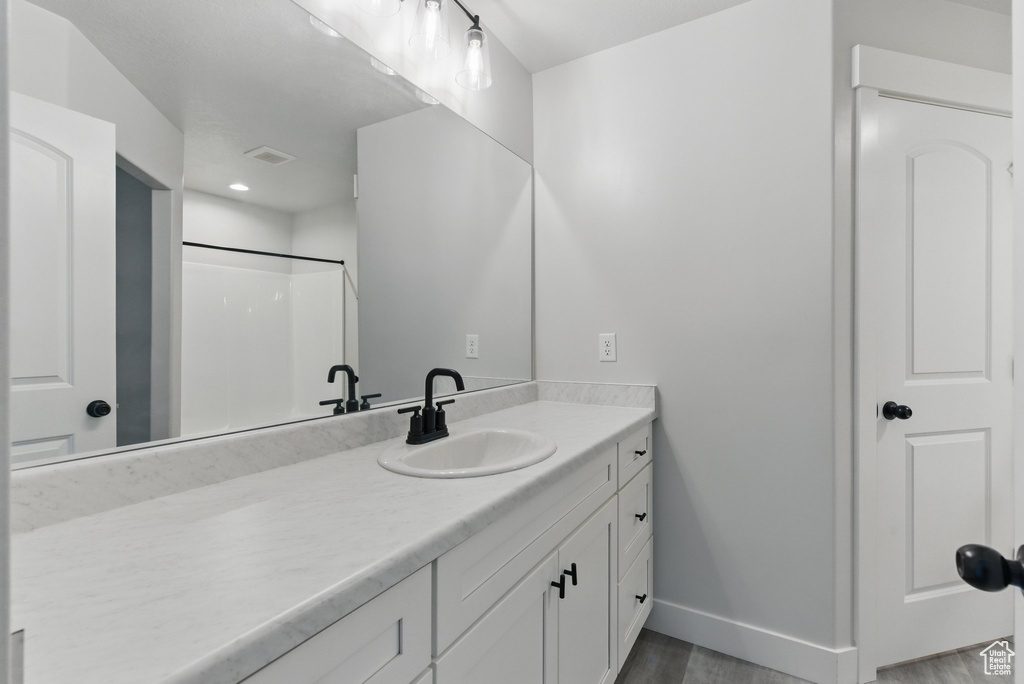 Bathroom with baseboards, wood finished floors, vanity, and recessed lighting