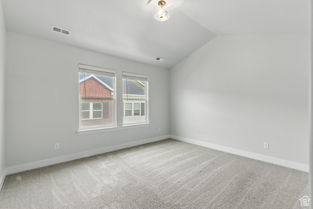 Unfurnished room featuring carpet flooring, vaulted ceiling, and baseboards