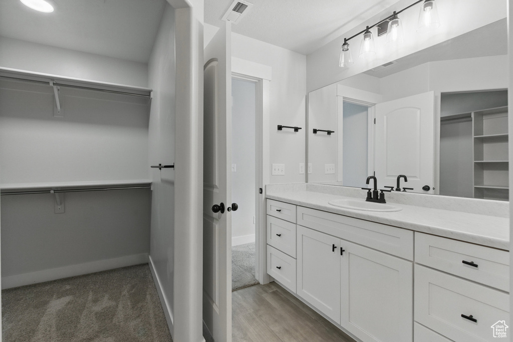 Bathroom with vanity, a walk in closet, and baseboards