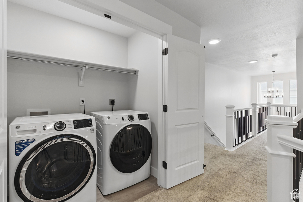 Laundry room featuring washing machine and clothes dryer, a chandelier, light colored carpet, and recessed lighting