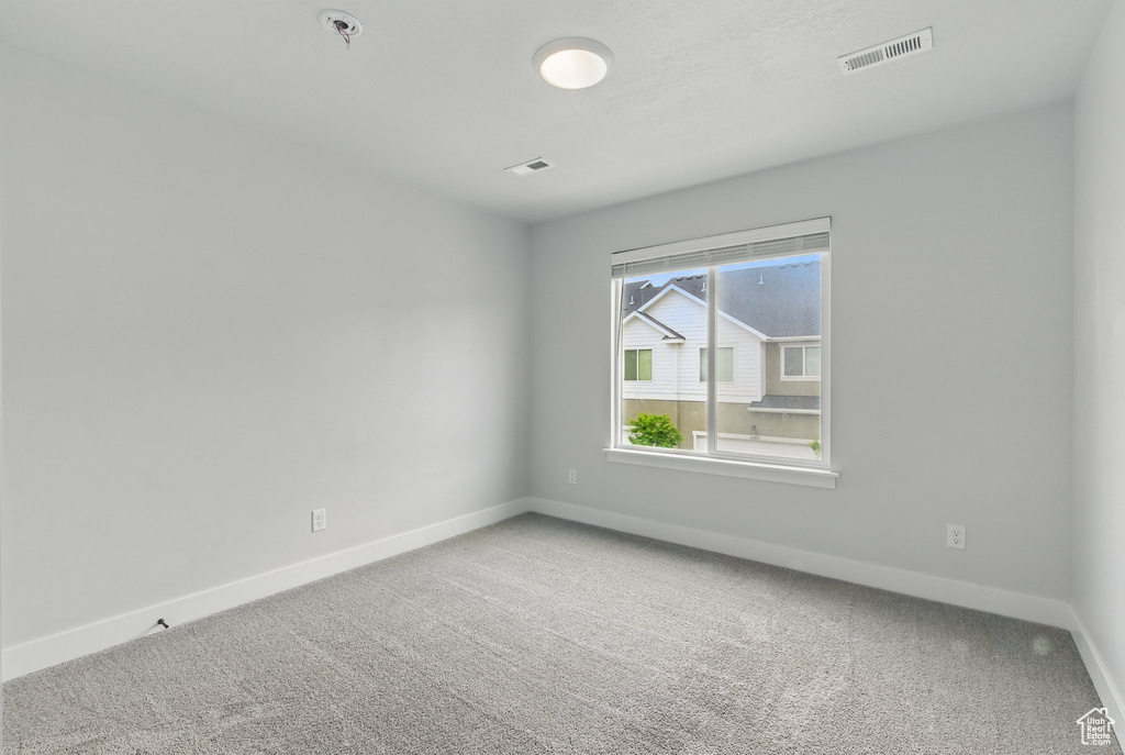 Empty room featuring baseboards, carpet, and fire sprinkler in ceiling
