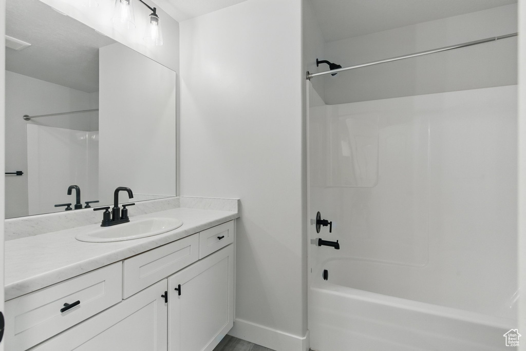 Full bath featuring baseboards, bathtub / shower combination, and vanity