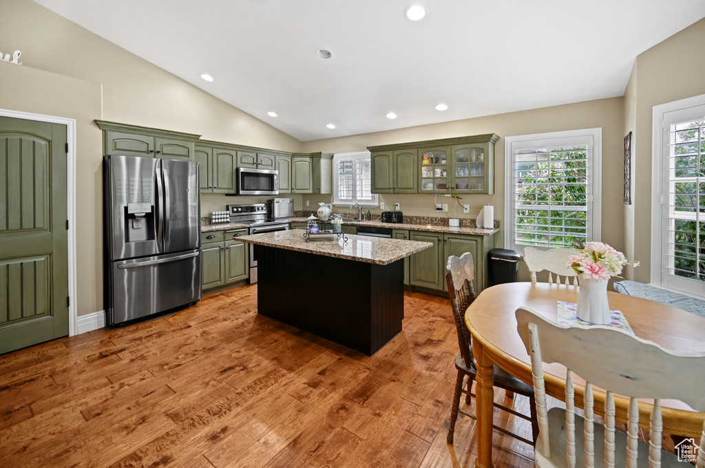 Kitchen featuring stainless steel appliances, green cabinets, vaulted ceiling, recessed lighting, and light wood finished floors