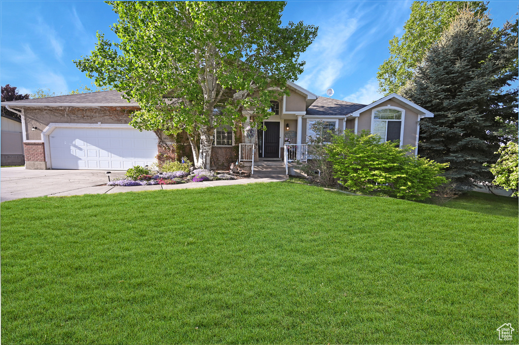 View of front facade with an attached garage, a front yard, concrete driveway, brick siding, and roof with shingles