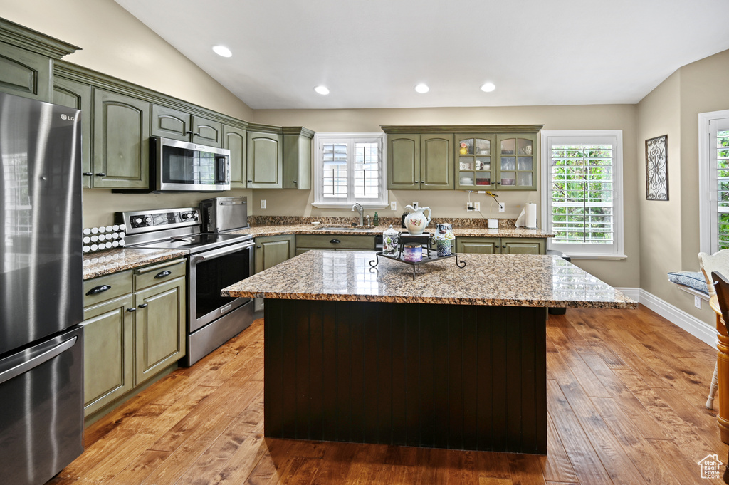 Kitchen featuring green cabinets, stainless steel appliances, light wood-style floors, light stone counters, and recessed lighting