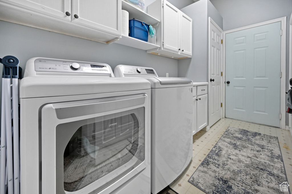 Laundry room featuring cabinet space, washing machine and clothes dryer, and light floors