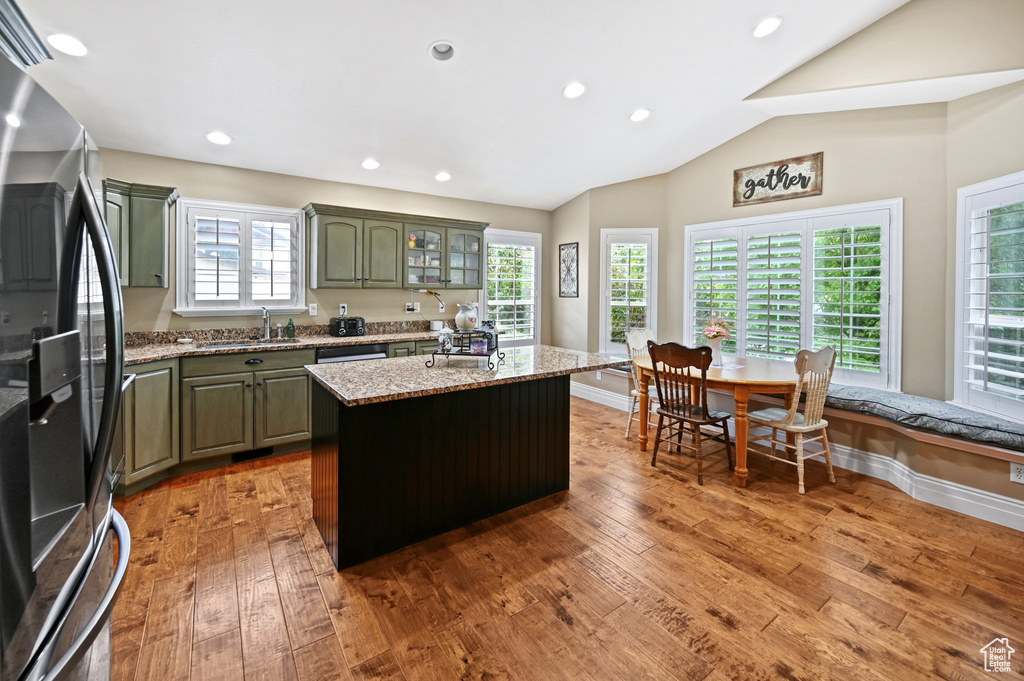 Kitchen featuring stainless steel fridge with ice dispenser, a sink, light wood-style floors, a kitchen island, and lofted ceiling