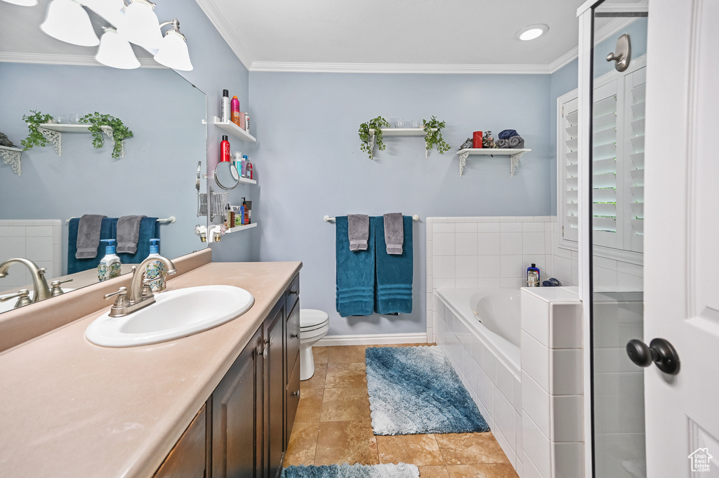 Full bath featuring ornamental molding, vanity, a garden tub, toilet, and baseboards