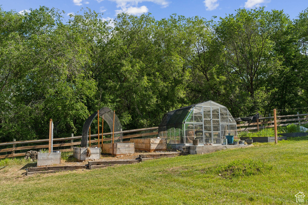 View of yard with a vegetable garden, a greenhouse, and an outdoor structure