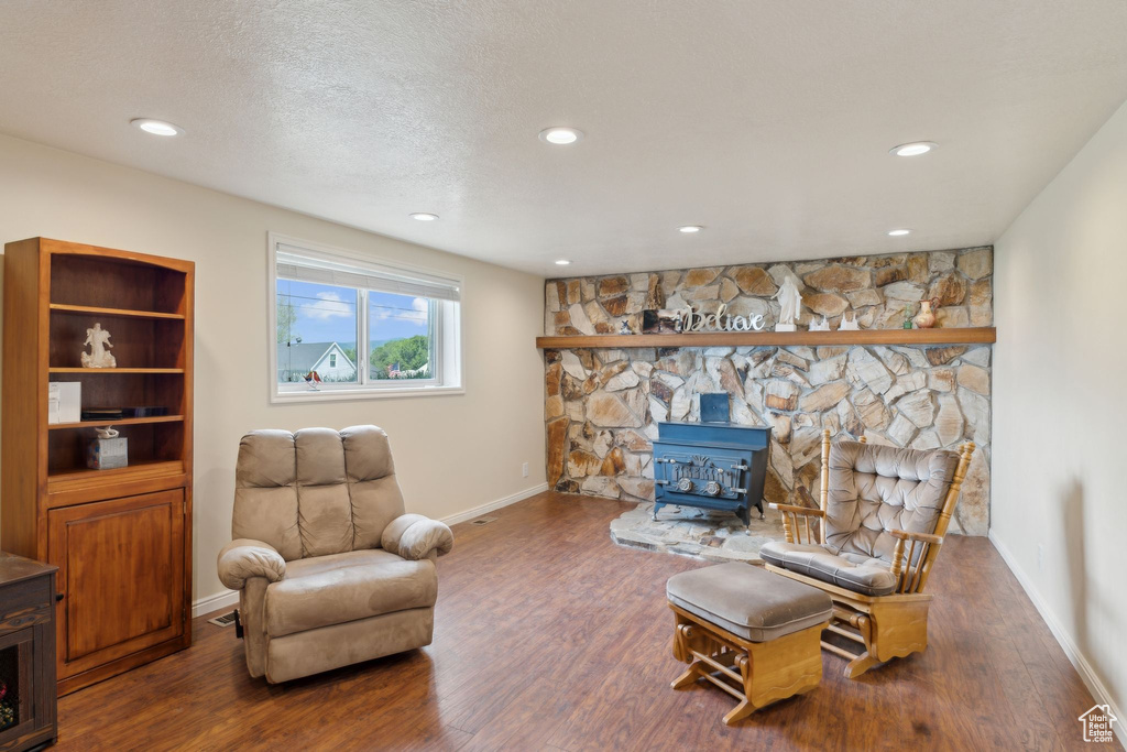 Sitting room with a wood stove, wood finished floors, baseboards, and recessed lighting