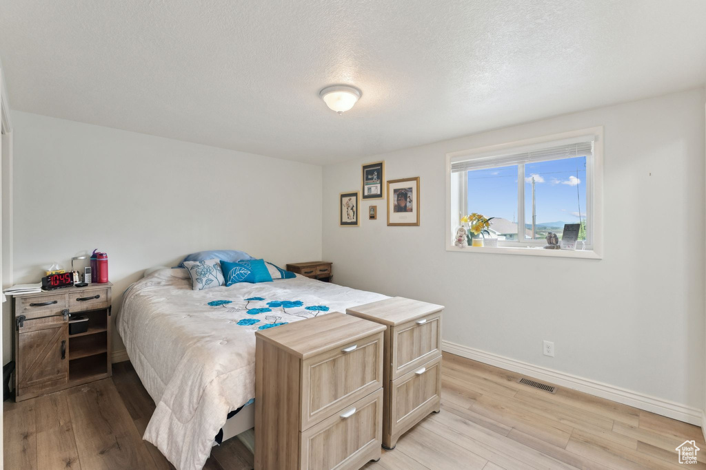 Bedroom featuring light wood-style floors, baseboards, and a textured ceiling