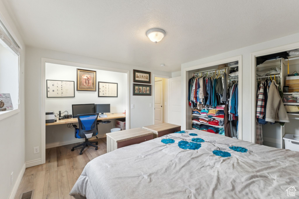 Bedroom with multiple closets, wood finished floors, an office area, and baseboards