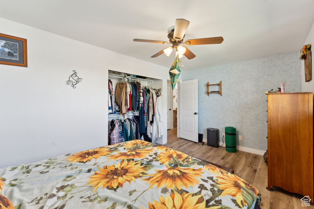 Bedroom featuring wood finished floors, a closet, baseboards, ceiling fan, and wallpapered walls