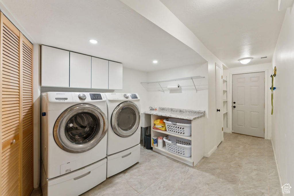 Washroom featuring washing machine and dryer, cabinet space, and recessed lighting