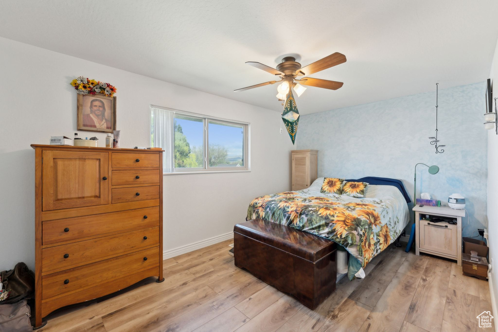 Bedroom featuring light wood-style floors, baseboards, and ceiling fan
