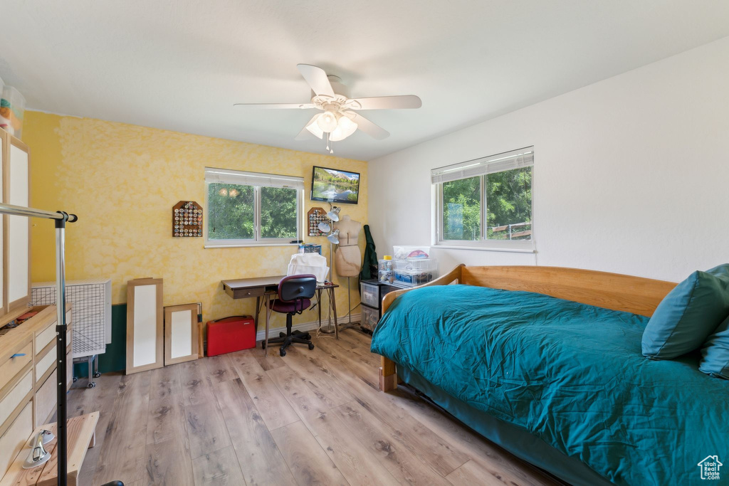 Bedroom featuring wood finished floors, an office area, and ceiling fan