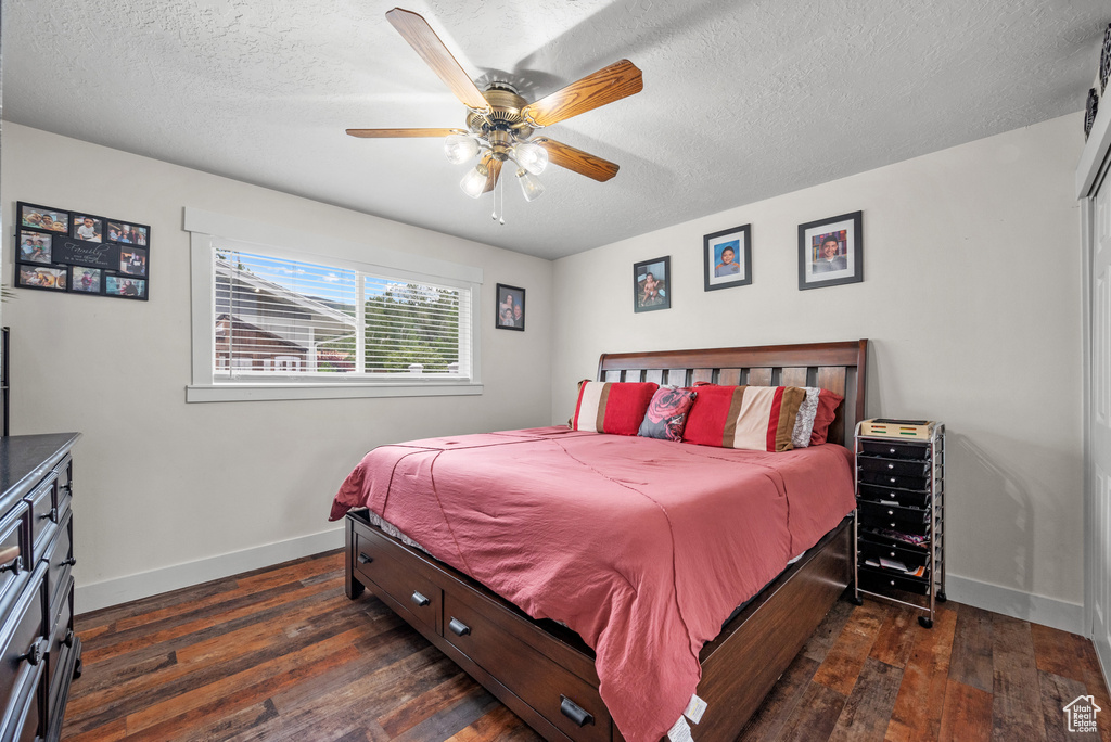 Bedroom featuring baseboards, dark wood-style floors, a textured ceiling, and ceiling fan