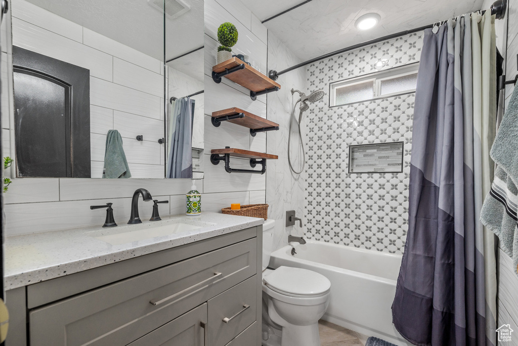 Full bathroom with shower / bath combo with shower curtain, toilet, vanity, and tasteful backsplash
