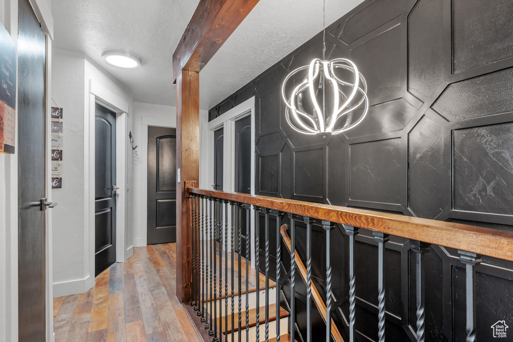 Hallway with a chandelier, light wood-style floors, and a textured ceiling