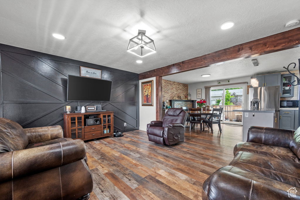 Living room with wood finished floors, a textured ceiling, recessed lighting, and a decorative wall