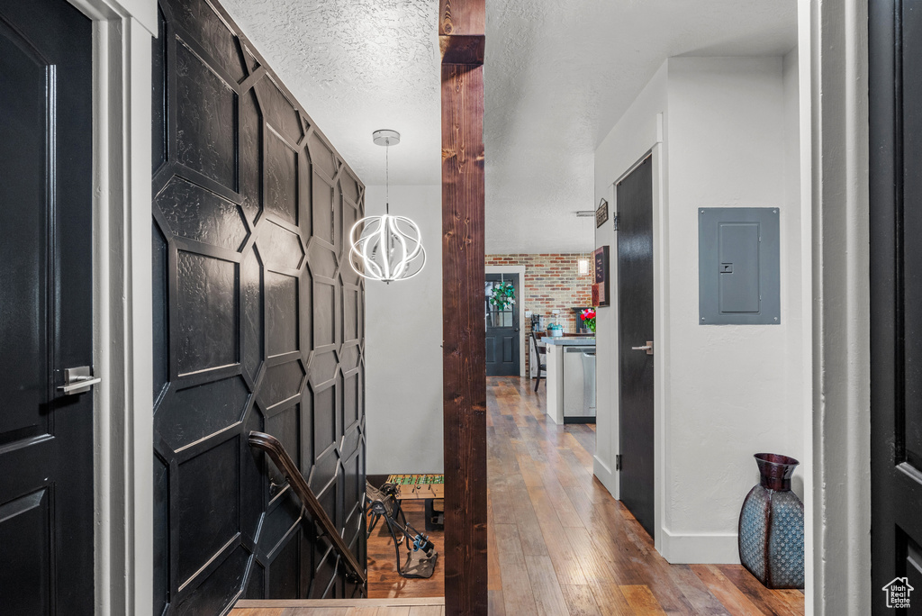 Hallway featuring electric panel, hardwood / wood-style flooring, and baseboards