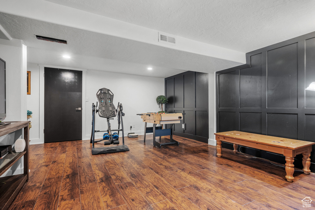 Exercise area with a decorative wall, wood finished floors, a textured ceiling, and baseboards