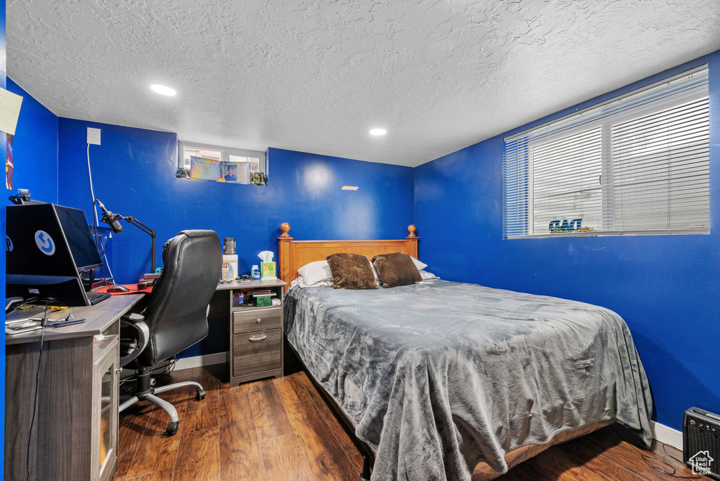 Bedroom with a textured ceiling, wood finished floors, baseboards, and recessed lighting