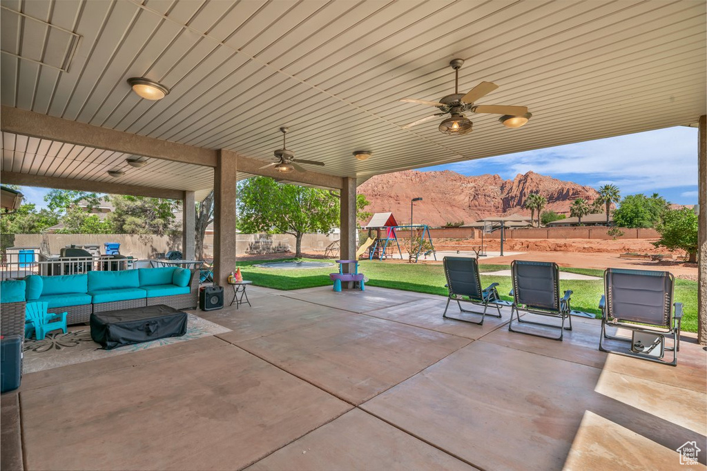 View of patio with outdoor lounge area, a playground, ceiling fan, and a mountain view