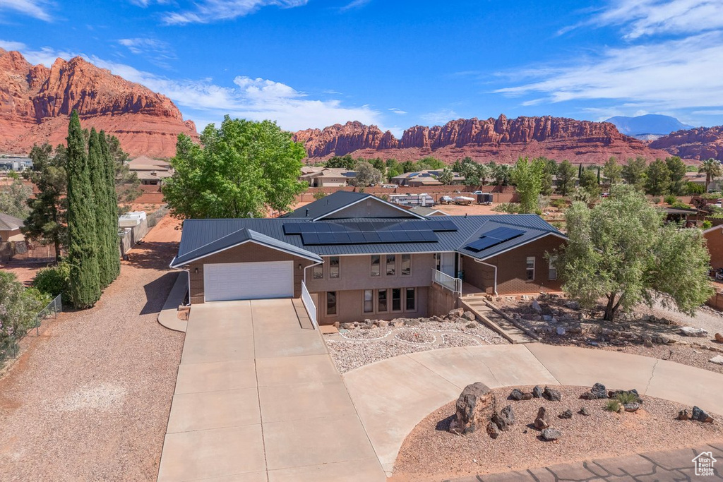 View of front of home with driveway, roof mounted solar panels, a mountain view, and metal roof