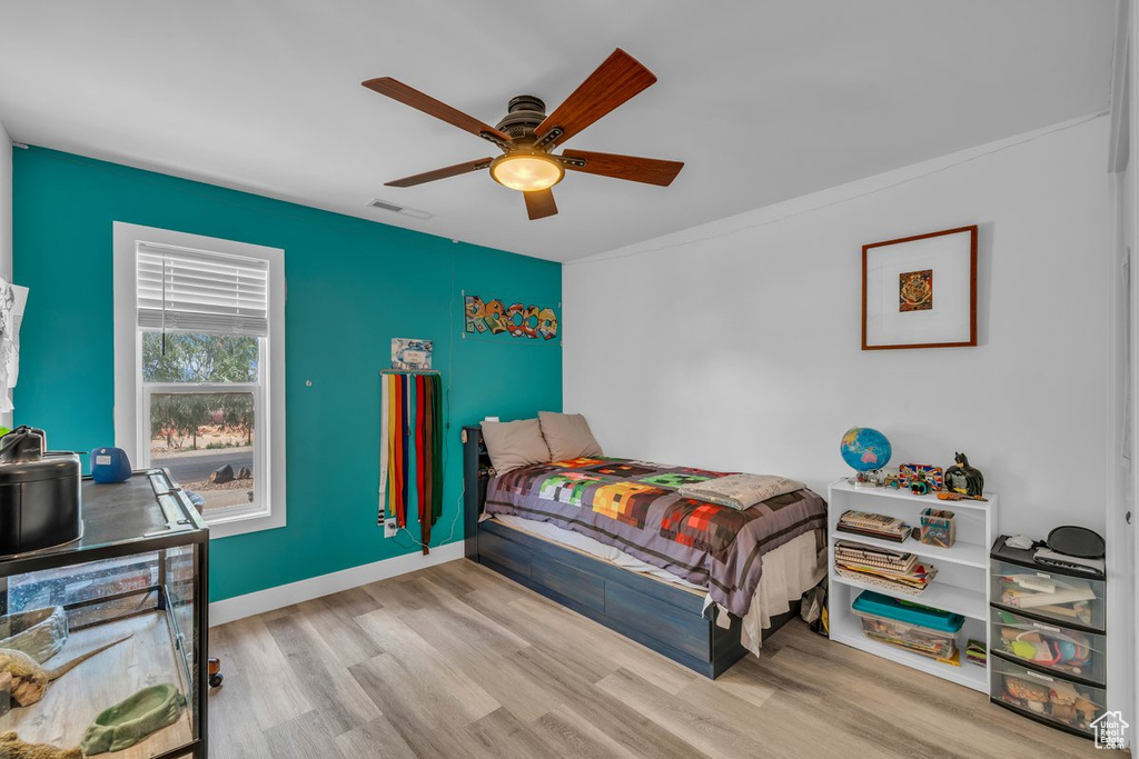 Bedroom featuring wood finished floors, ceiling fan, baseboards, and crown molding