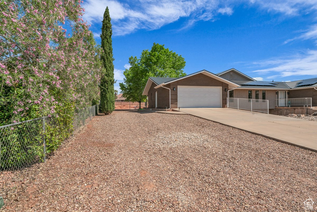 View of front of property with an attached garage, concrete driveway, fence, brick siding, and metal roof