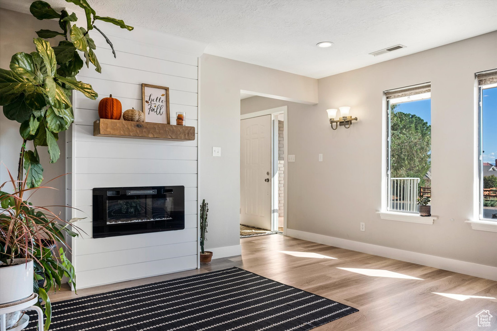 Unfurnished living room featuring wood finished floors, baseboards, a fireplace, recessed lighting, and a textured ceiling