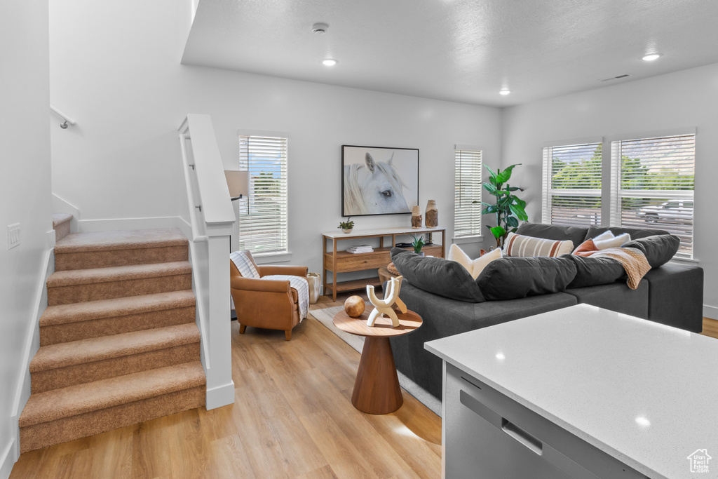 Living room featuring light wood finished floors, stairs, recessed lighting, and baseboards
