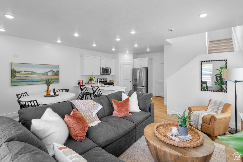 Living area featuring light wood-type flooring, recessed lighting, baseboards, and stairway
