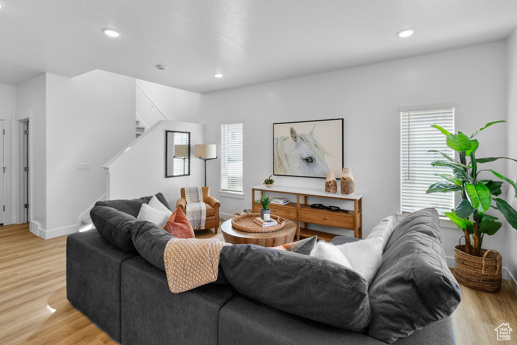 Living room featuring stairway, light wood-style floors, recessed lighting, and baseboards