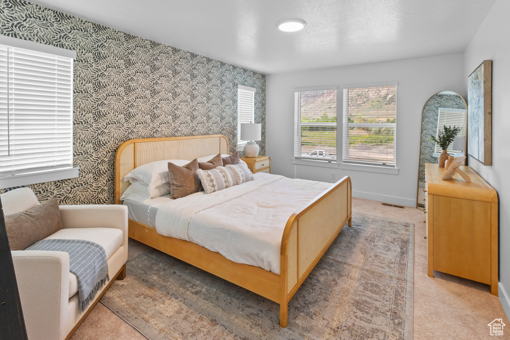Bedroom with wallpapered walls, baseboards, and light colored carpet