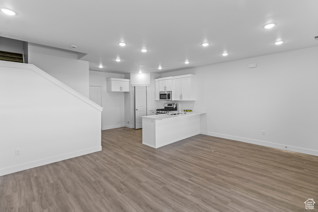 Kitchen with stainless steel appliances, a peninsula, recessed lighting, white cabinetry, and baseboards