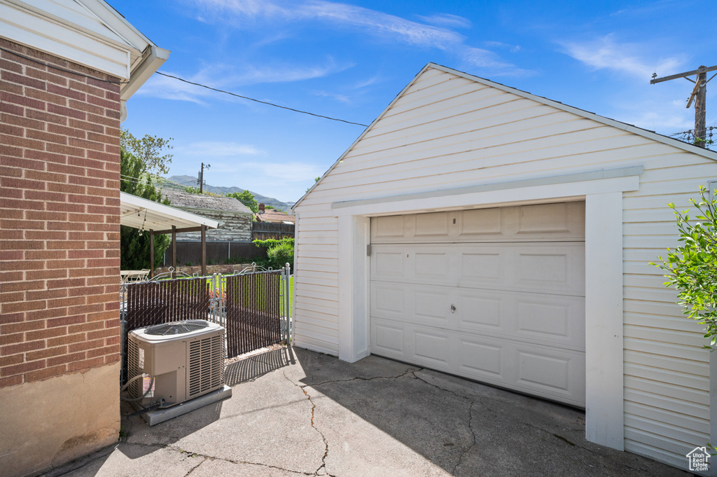 Detached garage with central AC, fence, a mountain view, and driveway