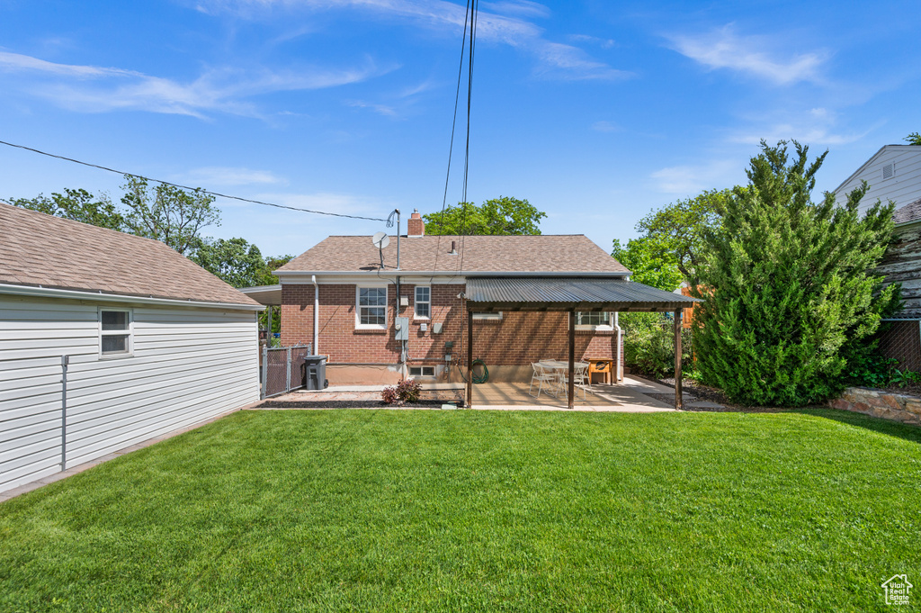 Rear view of property featuring a patio area, brick siding, a chimney, and roof with shingles
