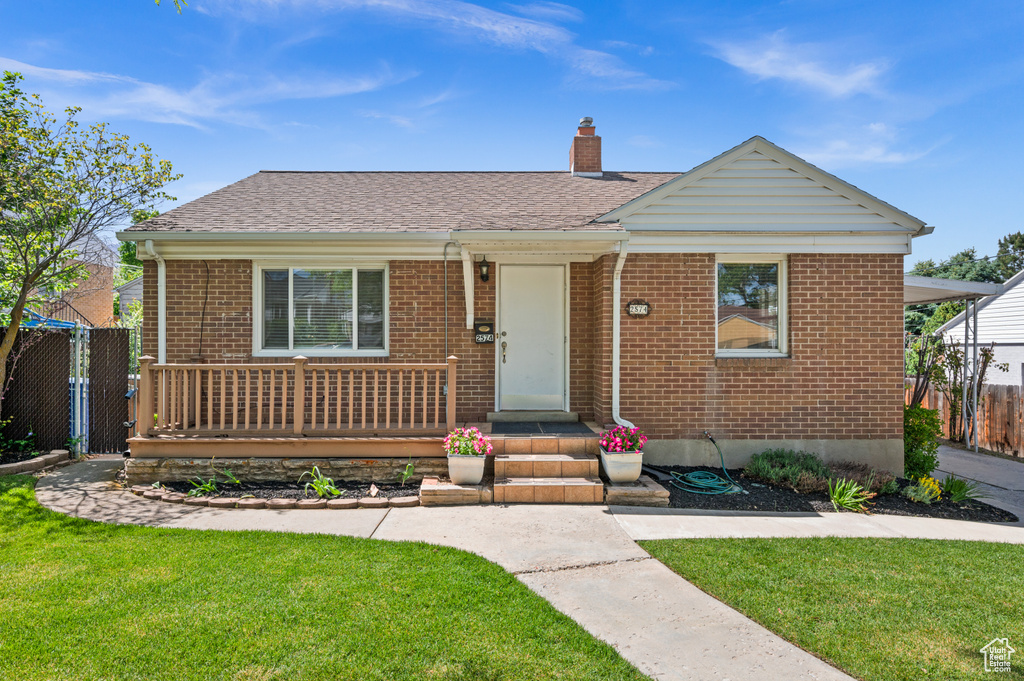 View of front of house featuring brick siding, a chimney, and roof with shingles