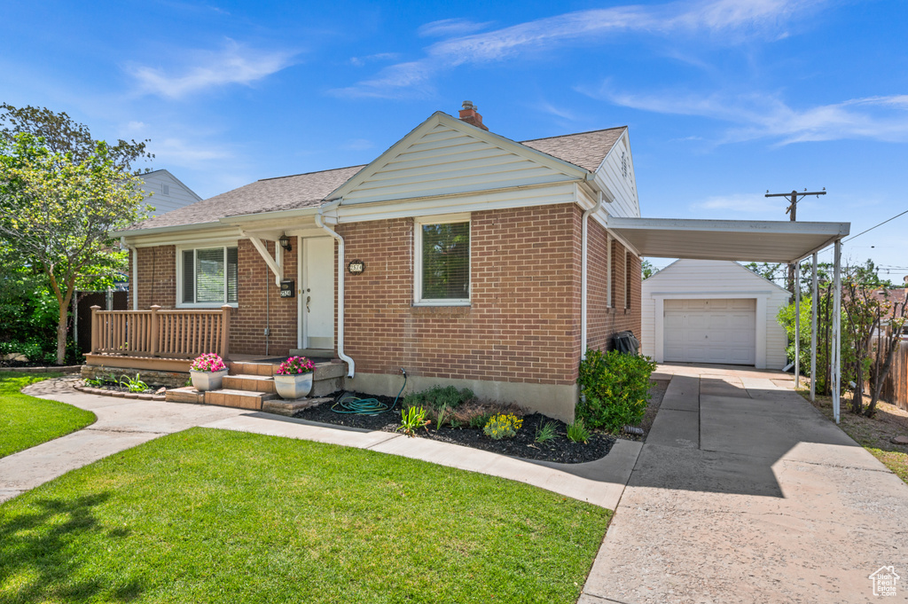 View of front of home with an outbuilding, a front yard, brick siding, driveway, and a garage