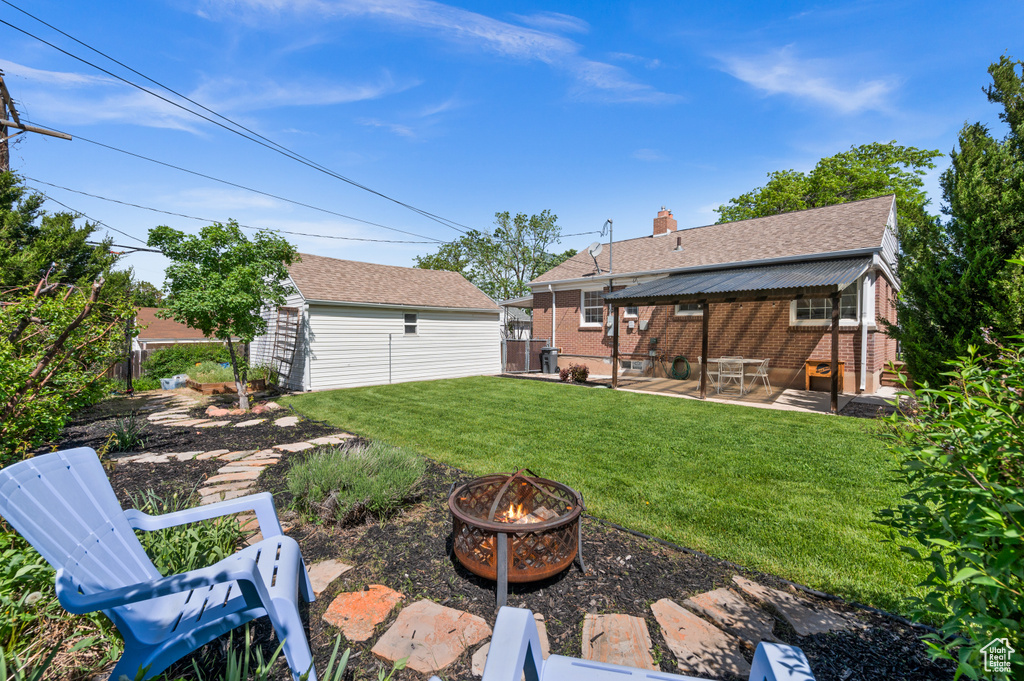 View of yard with an outdoor fire pit, a patio, and an outbuilding