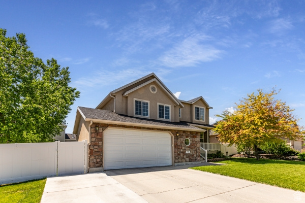 Traditional-style home with driveway, stone siding, and stucco siding