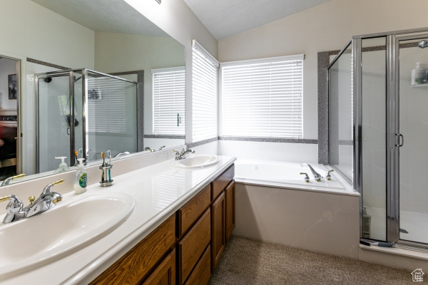 Bathroom featuring vaulted ceiling, a shower stall, a bath, and double vanity