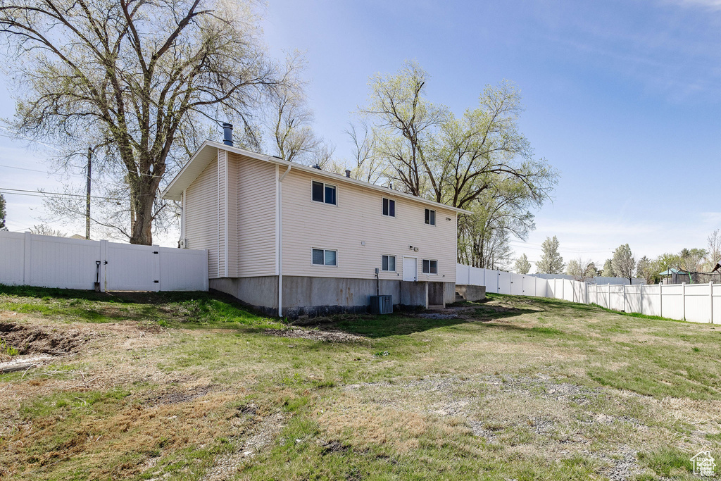 Rear view of property featuring a gate and cooling unit