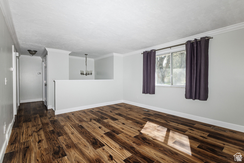 Unfurnished room with a chandelier, dark wood-type flooring, baseboards, and ornamental molding