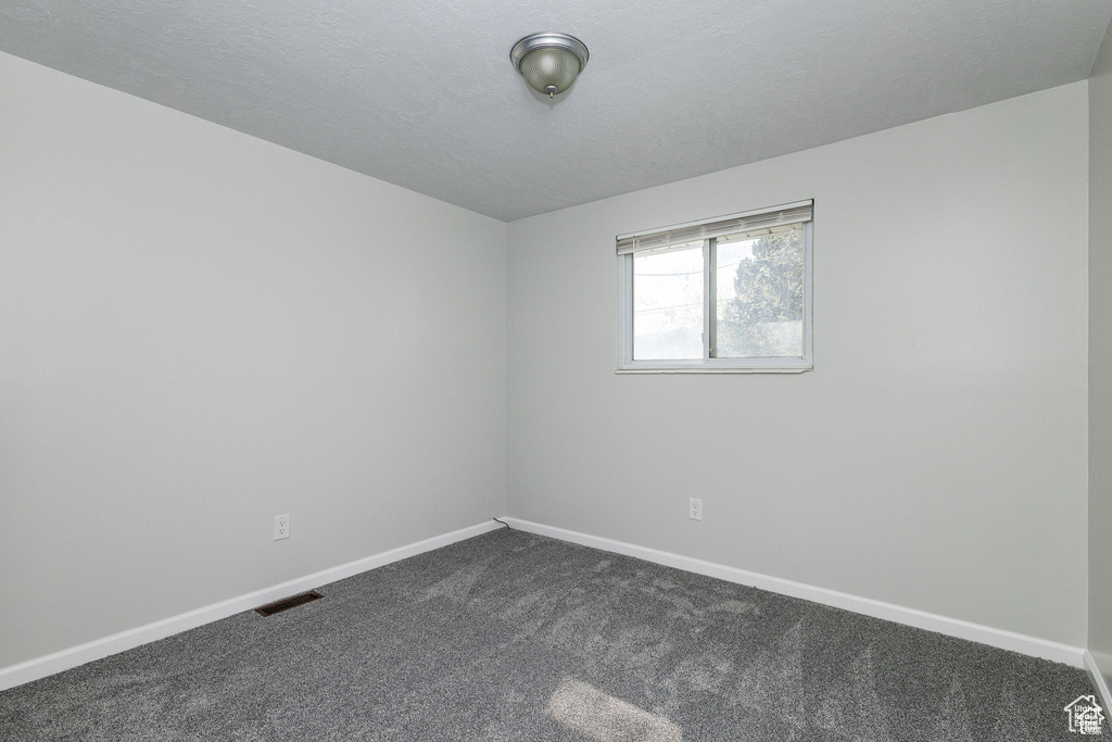 Empty room featuring dark colored carpet and baseboards