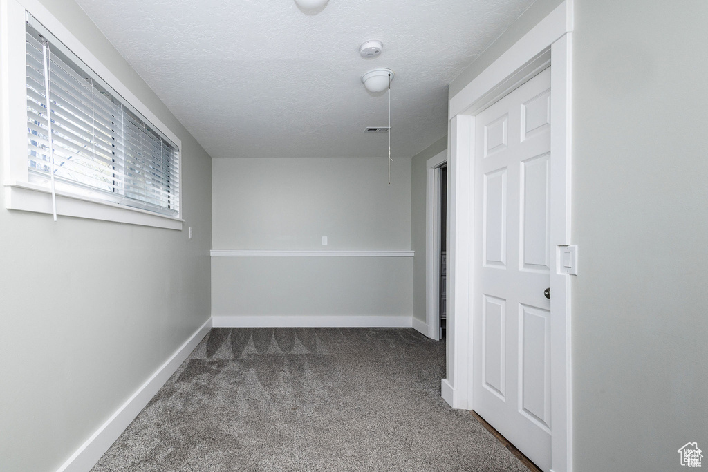 Carpeted spare room featuring baseboards and a textured ceiling