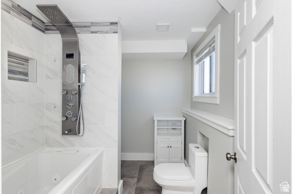 Bathroom featuring toilet, baseboards, and a combined bath / shower with jetted tub